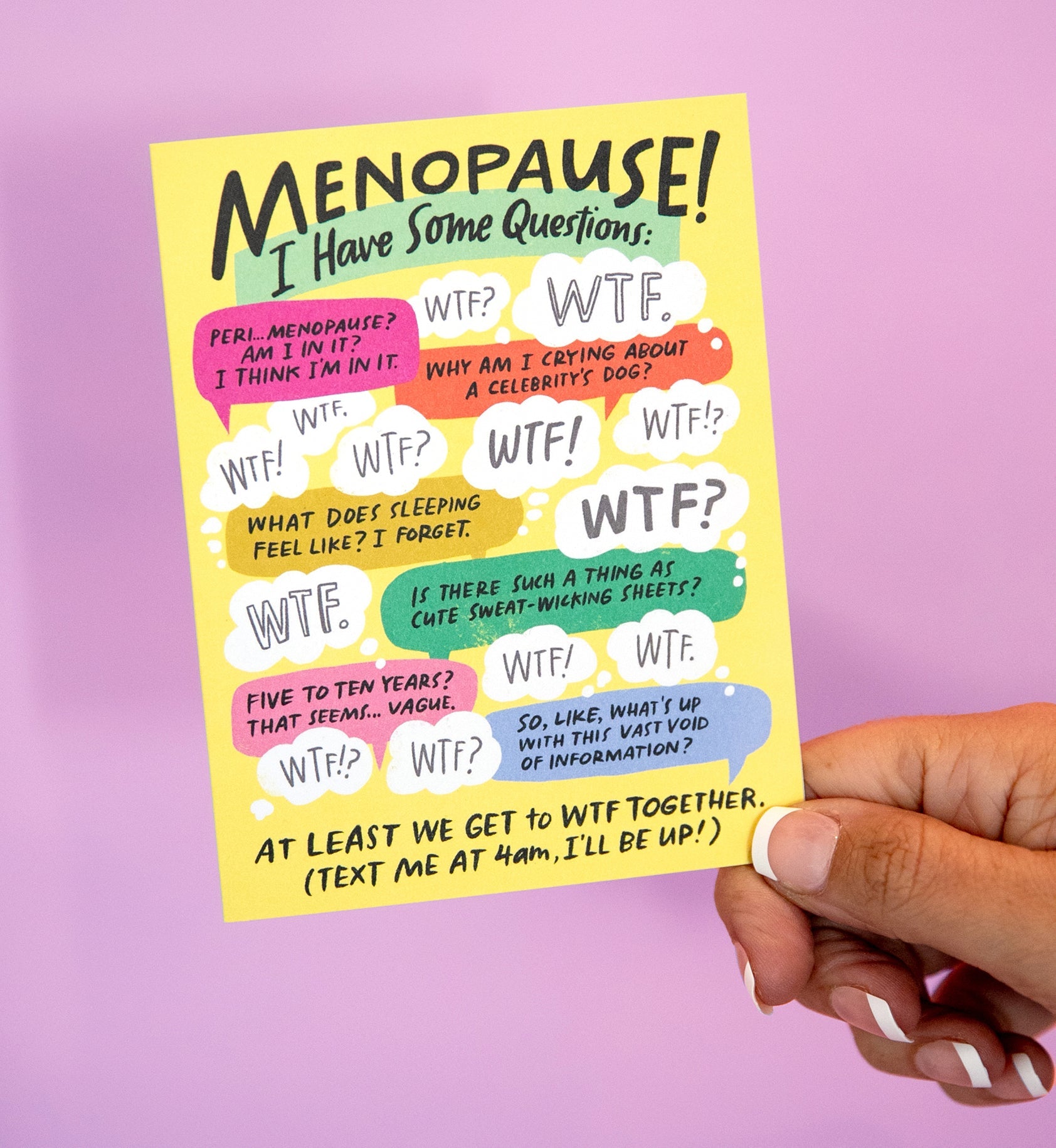 Hand holding an Em & Friends greeting card that reads 'I have some questions about this whole menopause thing...' in bold black letters on a white background with a colorful, abstract border in shades of pink, orange, and blue.