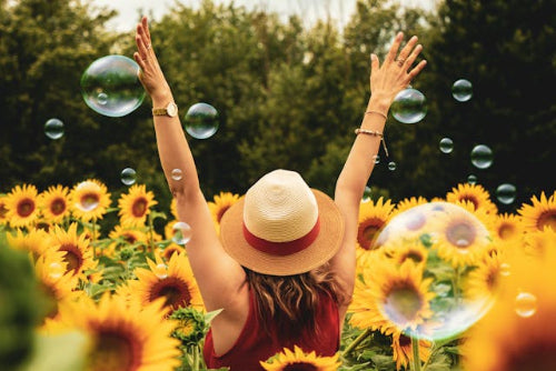 Woman walking through a sunflower field with bubbles