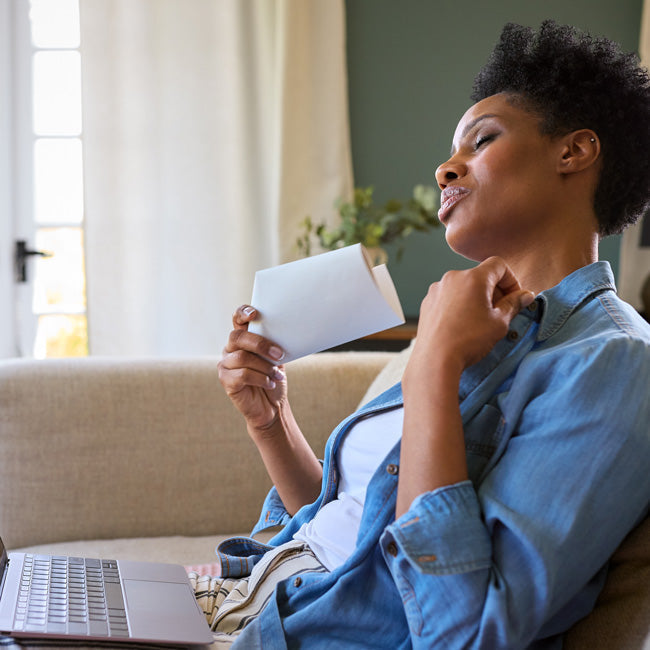 Menopausal Mature Woman At Home With Laptop Having Hot Flush Fanning Herself