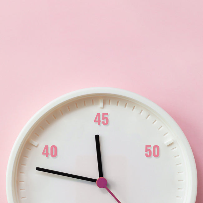 Numbers 40, 45 and 50 years and white clock dial on pink background. Age and periods of menopause.