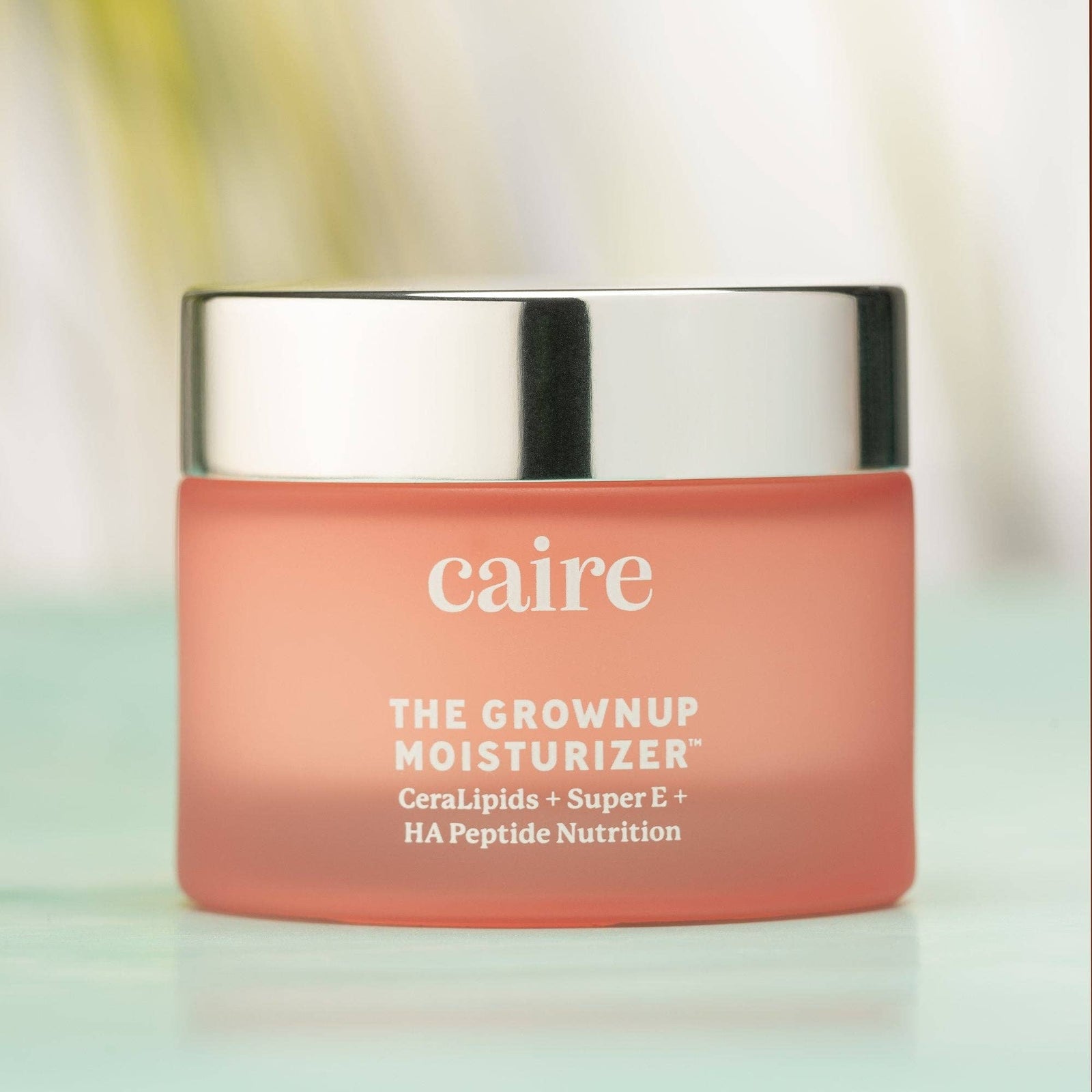 Caire Beauty The Grown Up Moisturizer product details, including sizes 15 ML | 0.5 OZ and 50 ML | 1.7 OZ. Doses per container: 50ML lasts 60-90 days, 15ML lasts 30 days. Serving size: 2 little dabs morning and night. Caire Healthy Skin Blend promotes 'Smooth, Lift, Super Glow.' Ingredients list includes Water, Shea Butter, Jojoba Seed Oil, Rice Bran Oil Extract, and various other plant and sea-based nutrients. Labels at the bottom read: 'Clean • Vegan • Plant & Sea Based Nutrition.