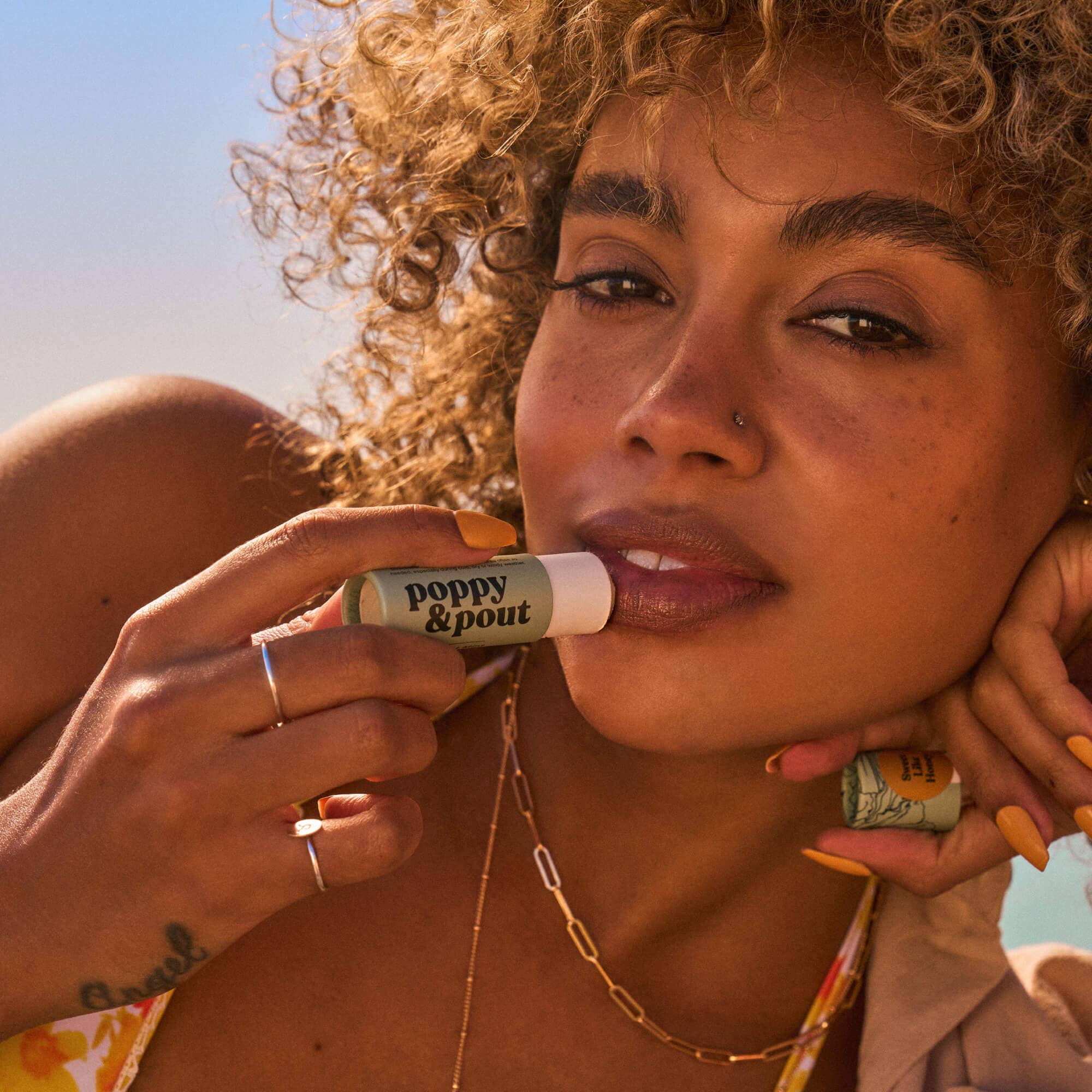 Close-up of woman applying Poppy & Pout Sweet Mint Lip Balm to her lips, emphasizing the hydrating, minty formula for soft, refreshed lips.