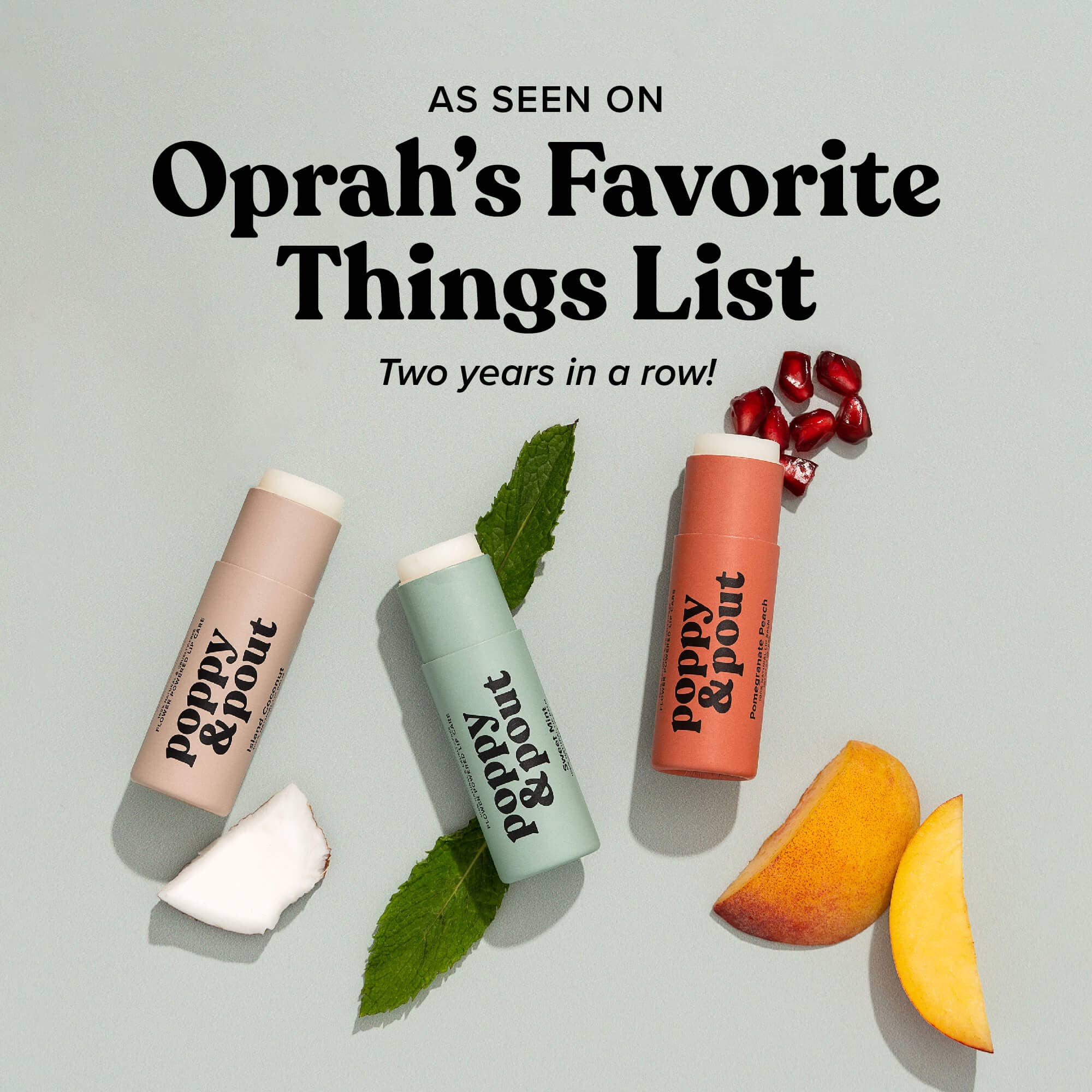 Three tubes of Poppy & Pout lip balm in shades representing different flavors, lying on a light green background. Text above reads 'As Seen on Oprah's Favorite Things List - Two years in a row!' The lip balms are placed alongside ingredients that match their flavors: coconut for the beige tube, mint for the green tube, and pomegranate and peach for the coral tube, showcasing the natural ingredients and popular recognition of the product.