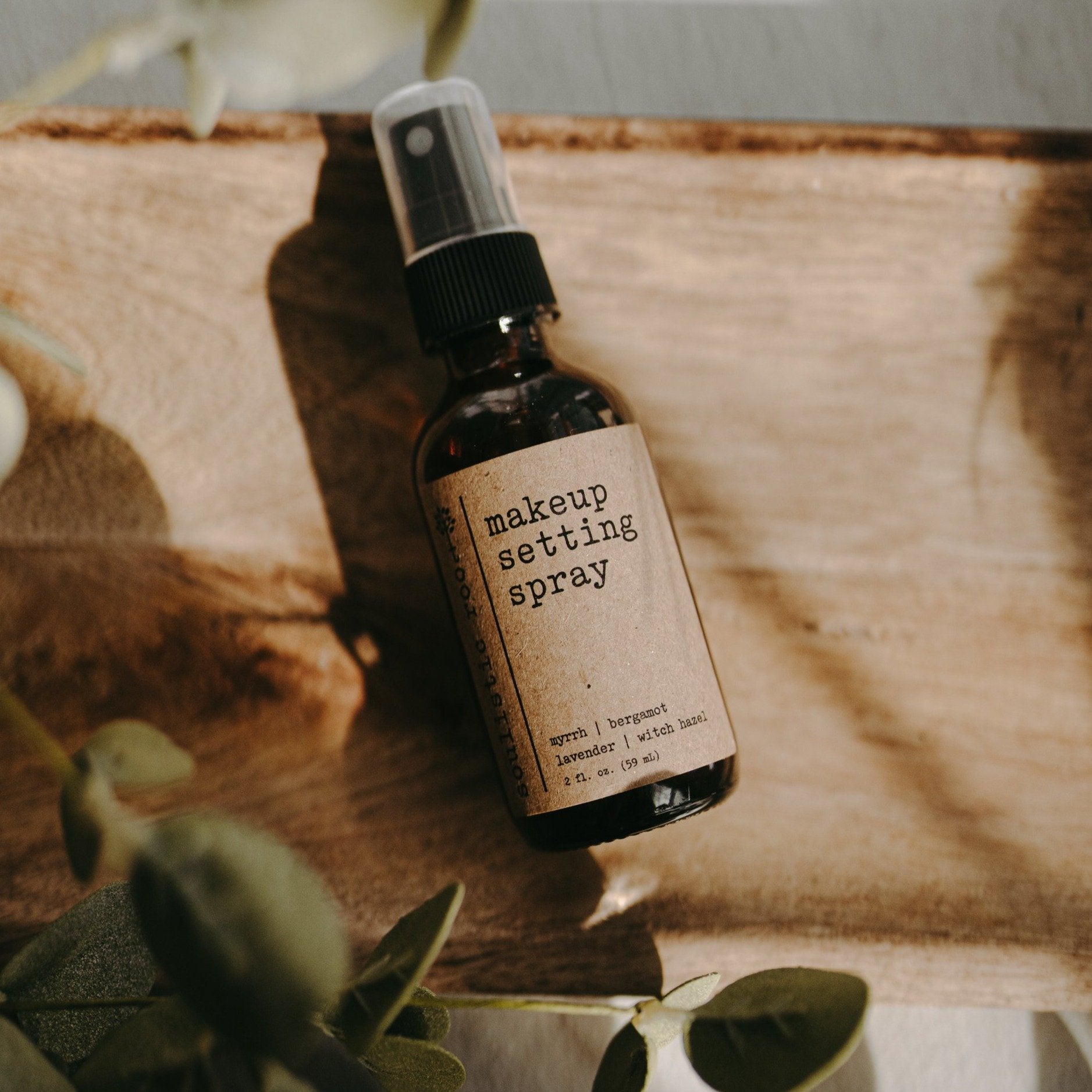 Soulistic Root Makeup Setting Spray amber spray bottle laying flat on a ppiece of wood