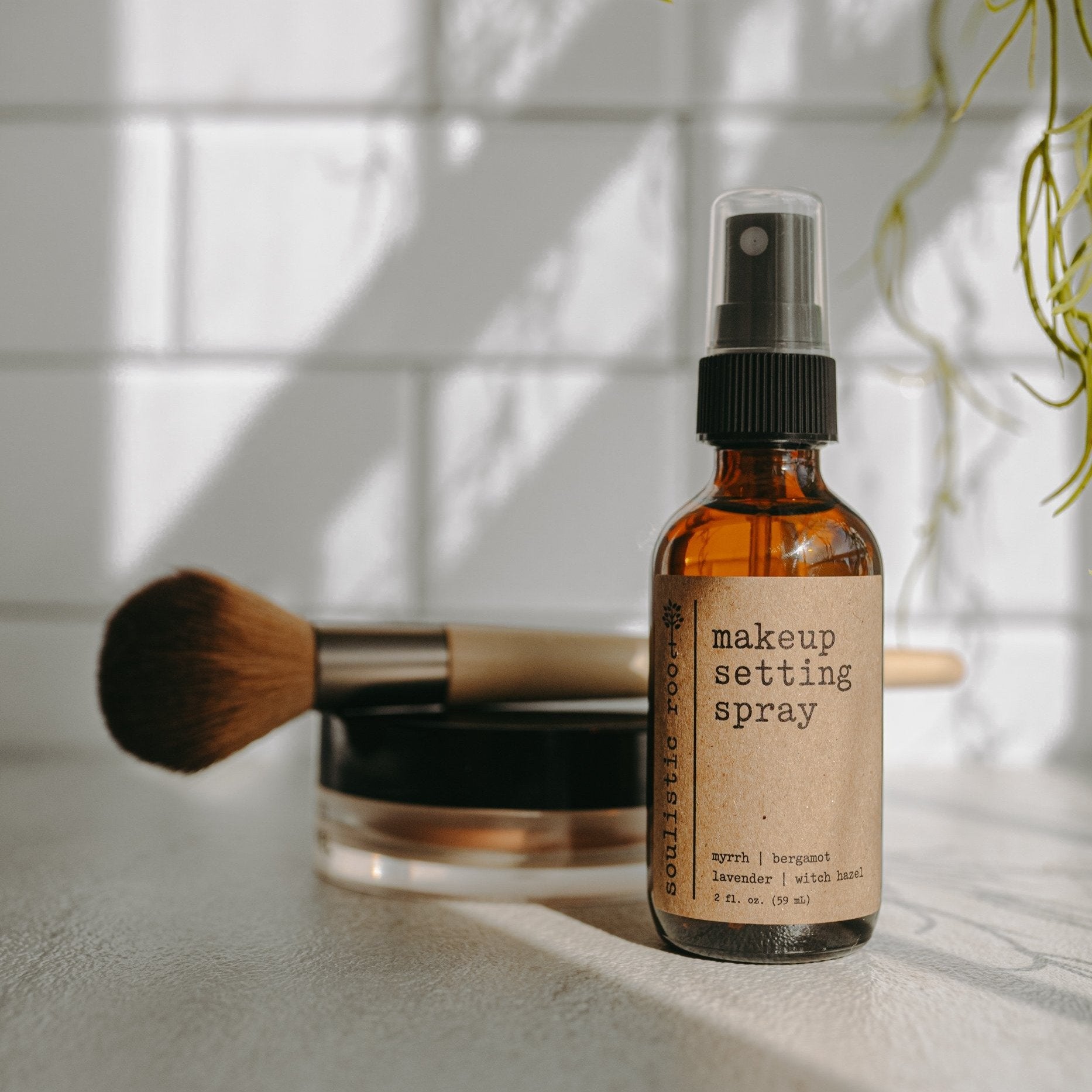 Soulistic Root Makeup Setting Spray bottle standing upright with makeup behind it in a bathroom setting