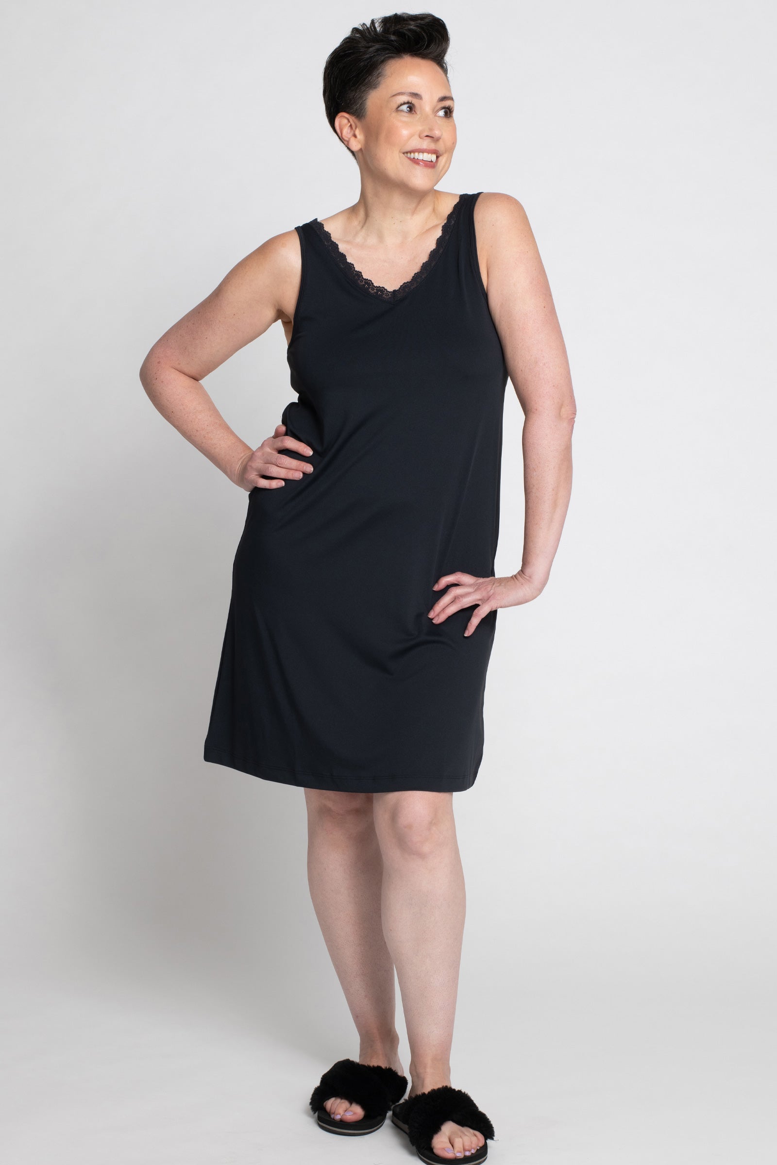 Angled front view of a woman wearing the Lace Trim Anti-Flush Nightie in black. The image highlights the nightie's lace detailing at the neckline and its flattering fit, designed to provide stylish comfort and cooling relief from hot flashes and night sweats.