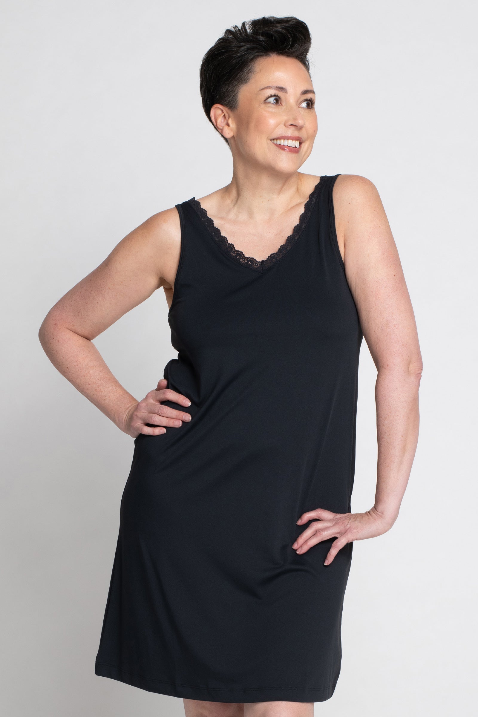 Woman wearing the Lace Trim Anti-Flush Nightie in black, relaxing at home. The image showcases the nightie's elegant lace detailing and breathable fabric, offering stylish comfort and cooling relief from hot flashes and night sweats.